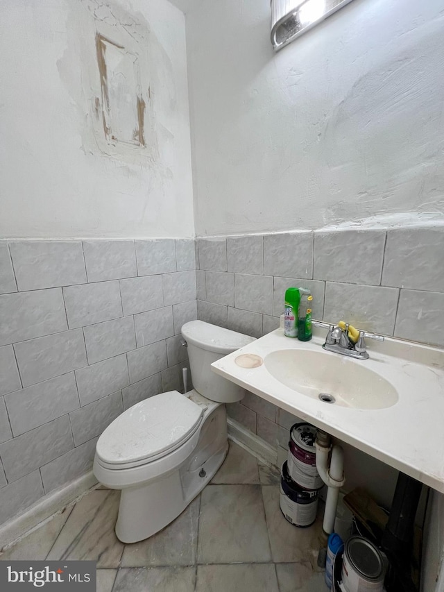 bathroom featuring tile walls, sink, toilet, and tile flooring