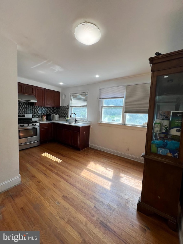 kitchen with gas range, sink, tasteful backsplash, and hardwood / wood-style flooring