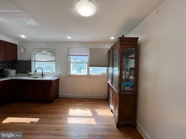 kitchen with backsplash, light hardwood / wood-style floors, and sink