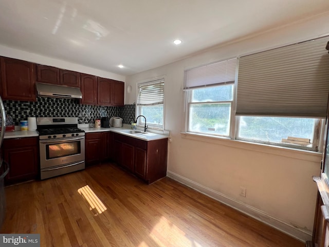 kitchen featuring hardwood / wood-style flooring, stainless steel gas range, tasteful backsplash, and sink