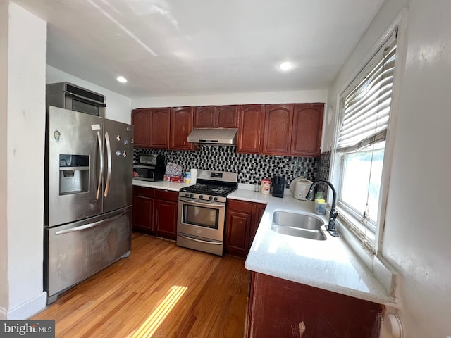 kitchen with sink, light hardwood / wood-style floors, tasteful backsplash, stainless steel appliances, and light stone countertops