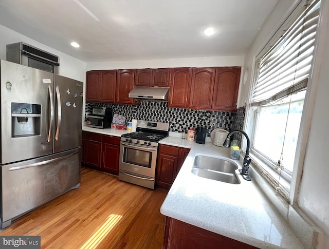 kitchen with backsplash, light hardwood / wood-style flooring, stainless steel appliances, and sink