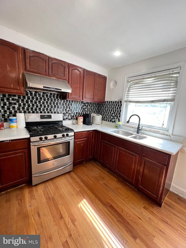 kitchen with sink, light hardwood / wood-style flooring, backsplash, and stainless steel gas stove