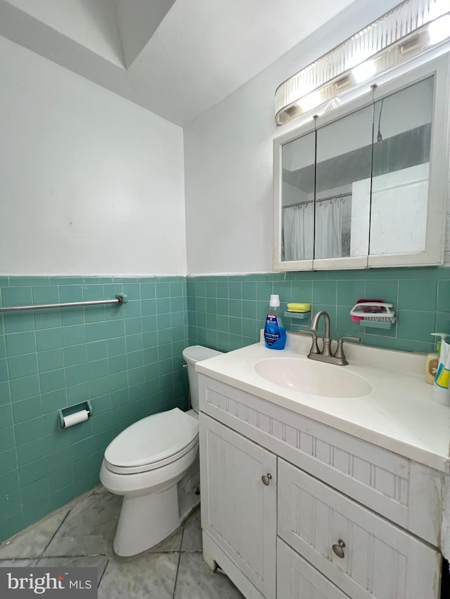 bathroom featuring tile flooring, oversized vanity, tile walls, and toilet