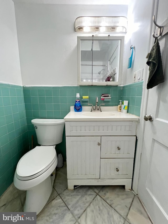 bathroom with tile walls, toilet, tile floors, and vanity