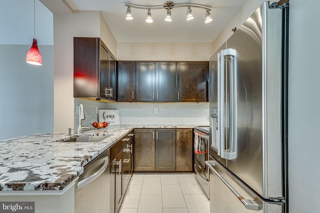 kitchen with light stone countertops, stainless steel appliances, backsplash, hanging light fixtures, and kitchen peninsula