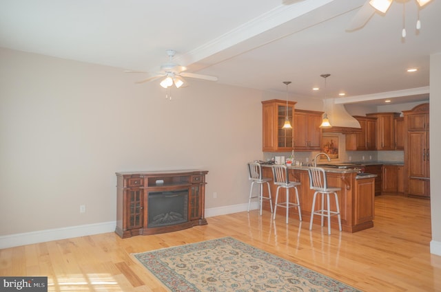 kitchen featuring a breakfast bar area, kitchen peninsula, light hardwood / wood-style floors, and custom range hood