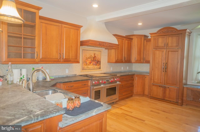 kitchen with premium range hood, range with two ovens, crown molding, tasteful backsplash, and light hardwood / wood-style floors