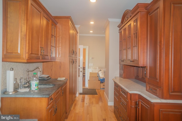 kitchen featuring sink, backsplash, light wood-type flooring, stone countertops, and ornamental molding