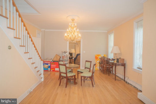 dining space with light hardwood / wood-style floors, crown molding, baseboard heating, and a chandelier