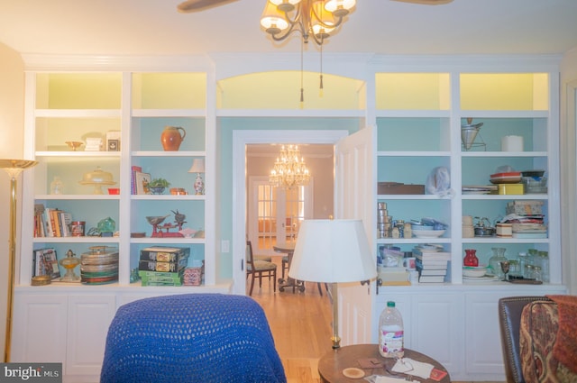 living area featuring hardwood / wood-style floors, built in features, and a notable chandelier