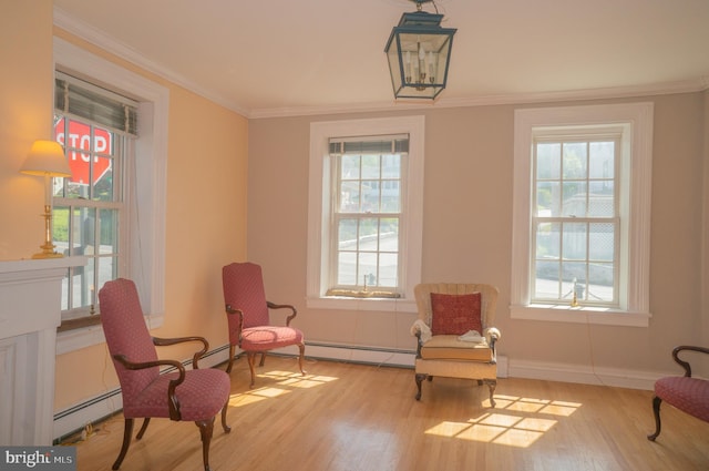 sitting room with baseboard heating, light hardwood / wood-style flooring, plenty of natural light, and ornamental molding