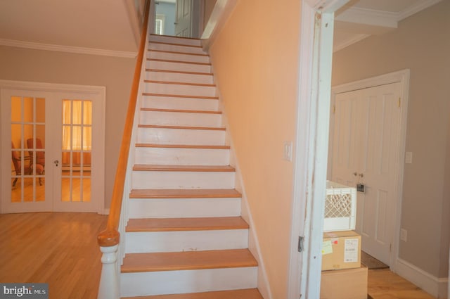 staircase featuring crown molding, french doors, and hardwood / wood-style flooring