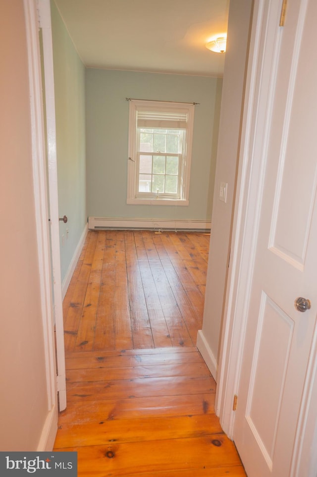 corridor featuring light wood-type flooring and a baseboard heating unit