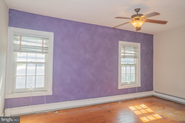 spare room featuring wood-type flooring, a baseboard radiator, and ceiling fan