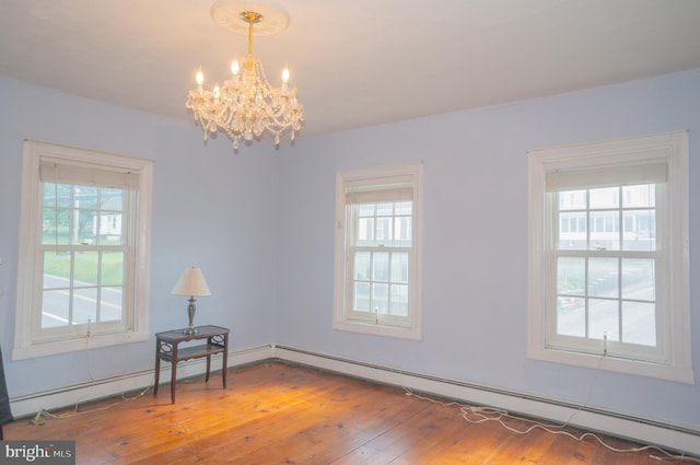 empty room with a baseboard heating unit, hardwood / wood-style flooring, and a notable chandelier