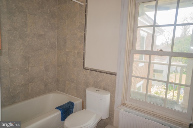 bathroom with a wealth of natural light, toilet, radiator, and tile walls