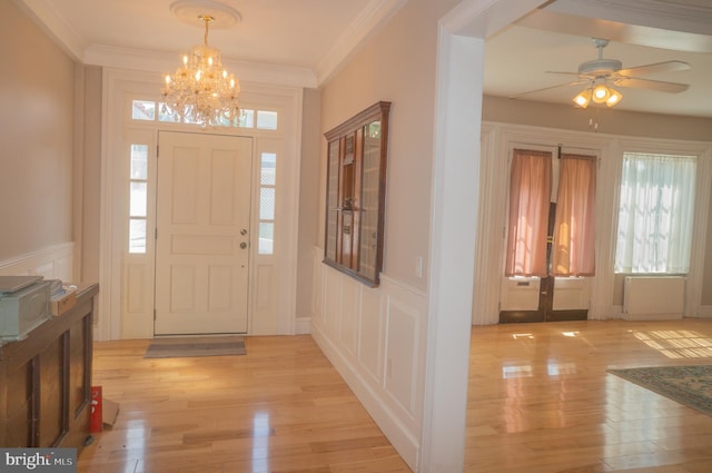 entrance foyer with french doors, light wood-type flooring, radiator, ceiling fan with notable chandelier, and crown molding