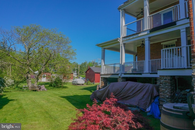 view of yard with ceiling fan and a balcony