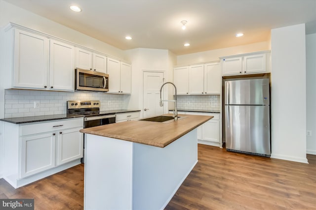 kitchen featuring appliances with stainless steel finishes, wood-type flooring, sink, and white cabinetry