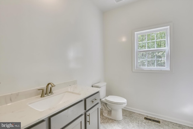 bathroom featuring tile floors, vanity, and toilet