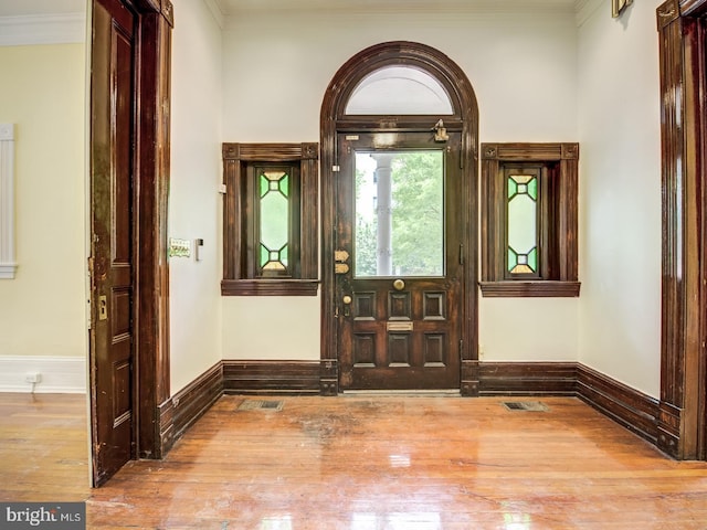 foyer featuring wood-type flooring and crown molding