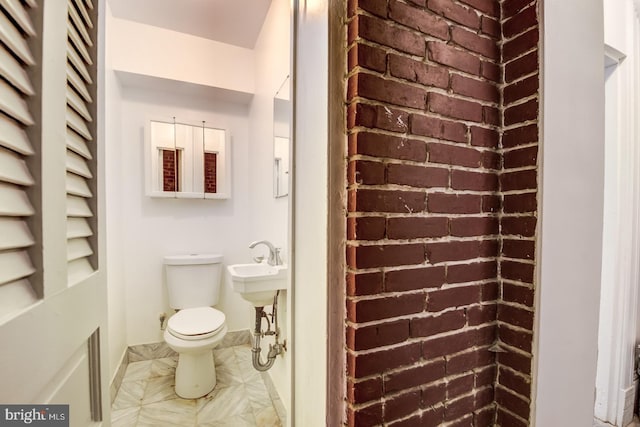 bathroom with toilet and brick wall