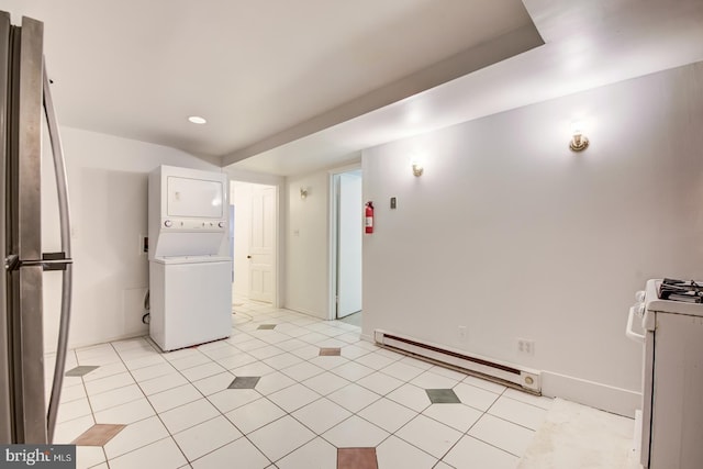 laundry area featuring stacked washing maching and dryer, baseboard heating, and light tile patterned floors