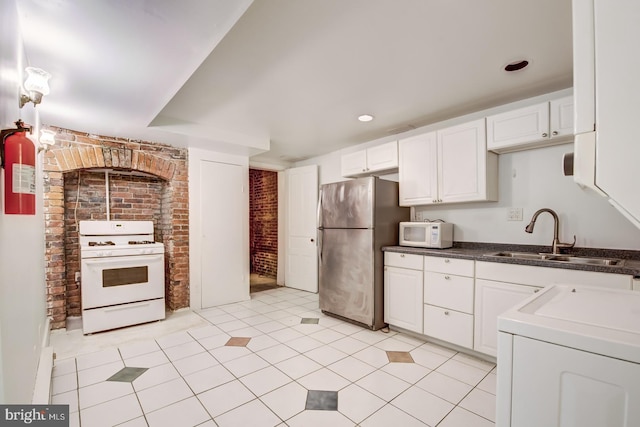 kitchen featuring light tile patterned flooring, white appliances, white cabinetry, and sink