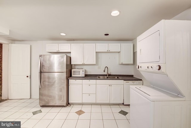 kitchen with stacked washer and clothes dryer, sink, light tile patterned floors, and white appliances