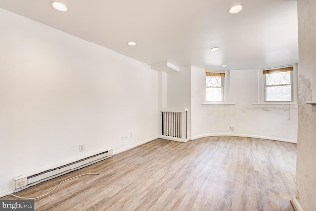 empty room with light hardwood / wood-style floors and a baseboard heating unit