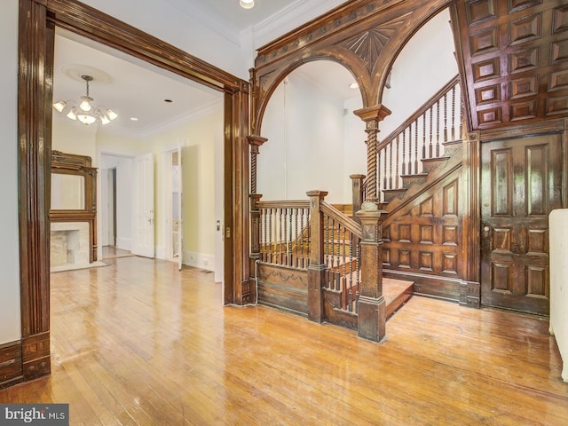 hallway featuring light hardwood / wood-style floors, crown molding, and an inviting chandelier