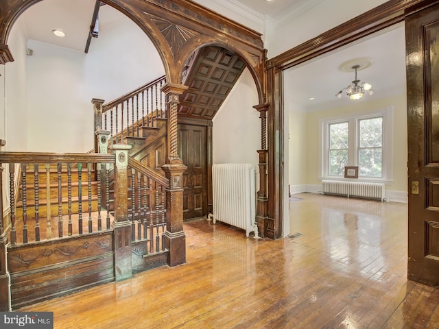 staircase featuring wood-type flooring, radiator, and crown molding