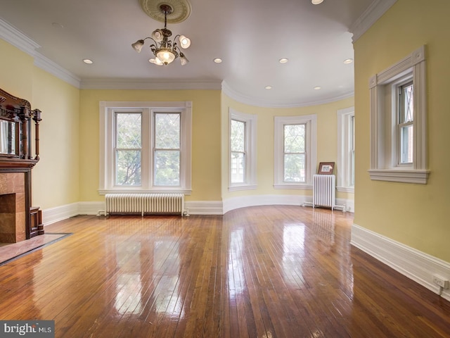 unfurnished living room with radiator heating unit, crown molding, and a wealth of natural light