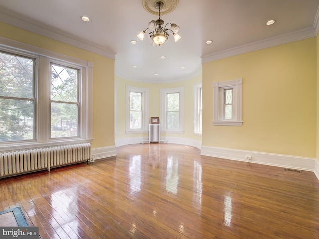 unfurnished living room featuring wood-type flooring, radiator heating unit, crown molding, and an inviting chandelier