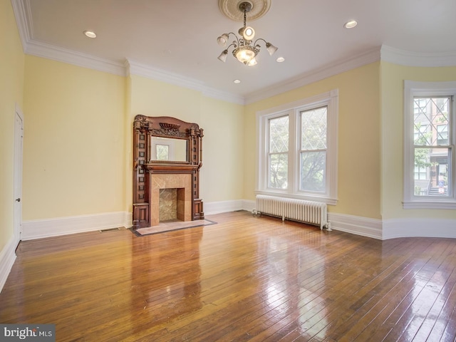 unfurnished living room featuring hardwood / wood-style flooring, plenty of natural light, radiator heating unit, and ornamental molding