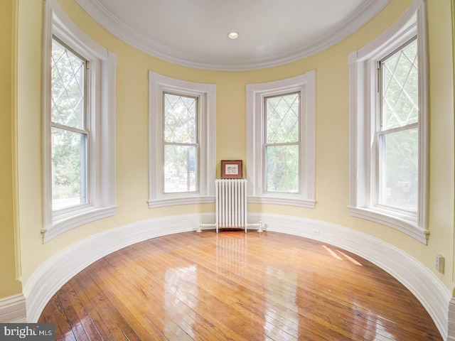 unfurnished room with radiator heating unit, ornamental molding, and wood-type flooring