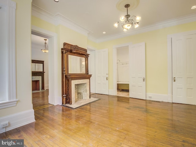 unfurnished living room with a premium fireplace, hardwood / wood-style floors, a chandelier, and ornamental molding