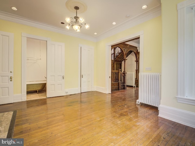 interior space with ornamental molding, radiator, a notable chandelier, and hardwood / wood-style floors