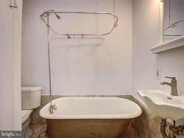 bathroom with a washtub, toilet, and sink