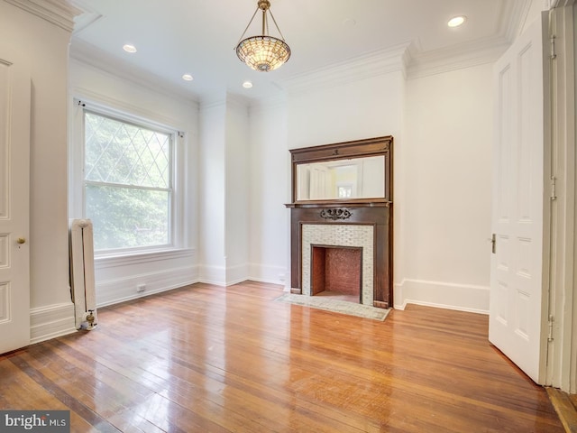 unfurnished living room with a fireplace, wood-type flooring, radiator heating unit, and crown molding