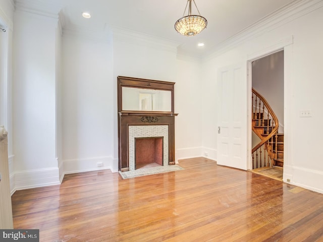 unfurnished living room featuring a fireplace, hardwood / wood-style flooring, and crown molding