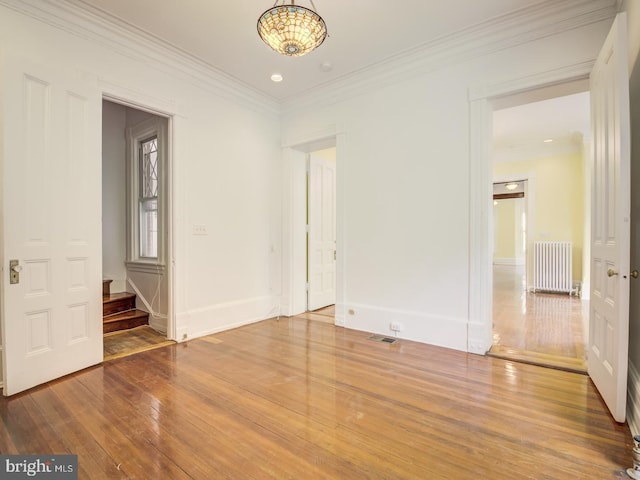 unfurnished room with radiator, crown molding, and hardwood / wood-style flooring