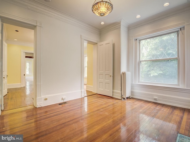 unfurnished room featuring radiator, crown molding, and light hardwood / wood-style flooring