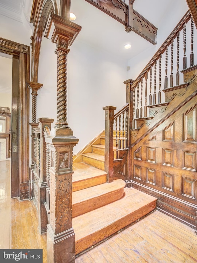 staircase with wood walls, hardwood / wood-style flooring, and ornamental molding