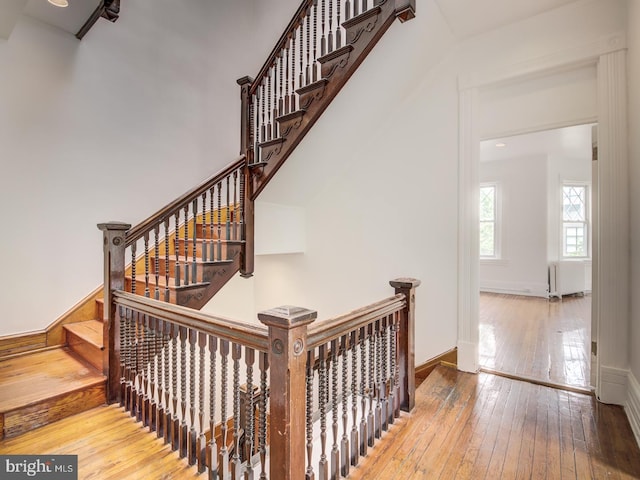 staircase with hardwood / wood-style flooring and radiator heating unit