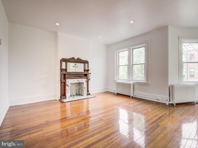 unfurnished living room featuring radiator heating unit and light hardwood / wood-style flooring