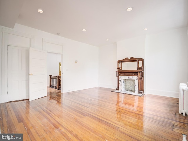 unfurnished living room featuring radiator heating unit and light hardwood / wood-style flooring