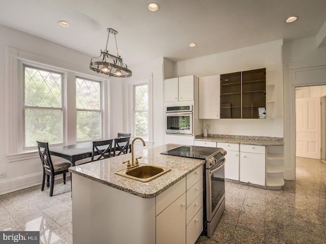 kitchen with pendant lighting, a kitchen island with sink, sink, white cabinetry, and stainless steel appliances