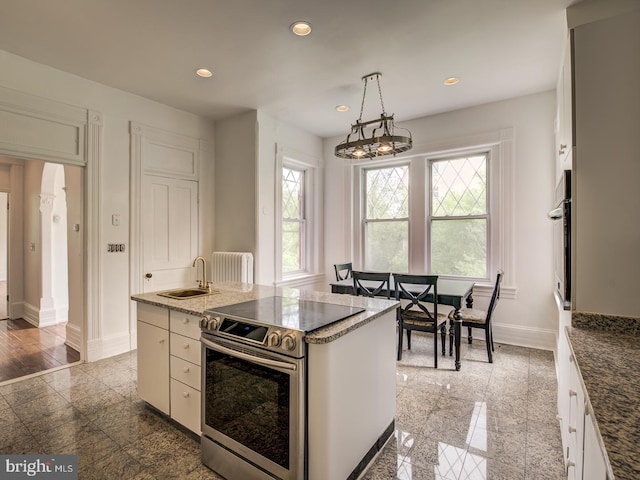 kitchen featuring pendant lighting, a center island, radiator, white cabinetry, and stainless steel appliances